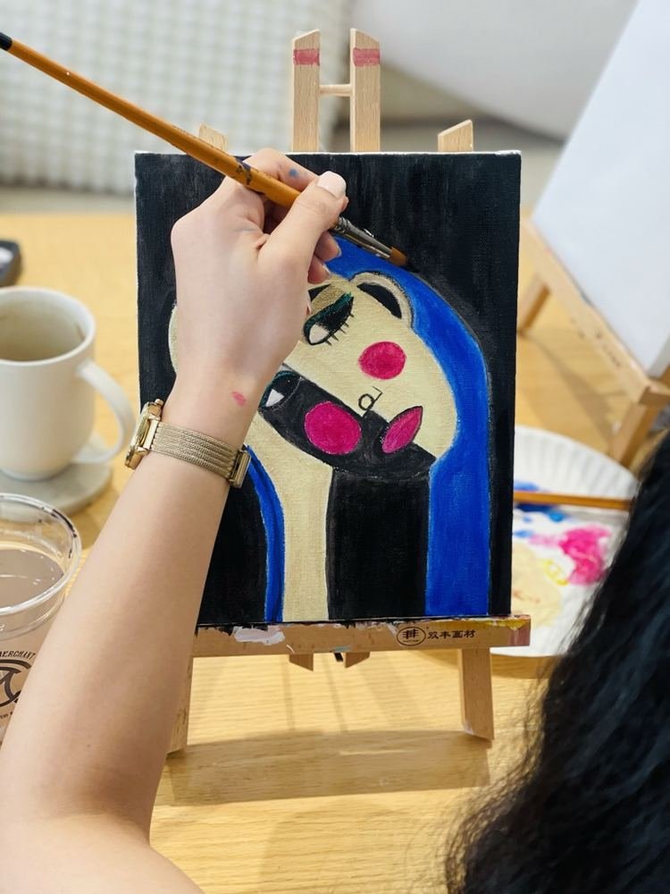 A hand painting a blue portrait